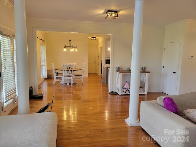 living room featuring light hardwood / wood-style flooring, ornamental molding, and ornate columns