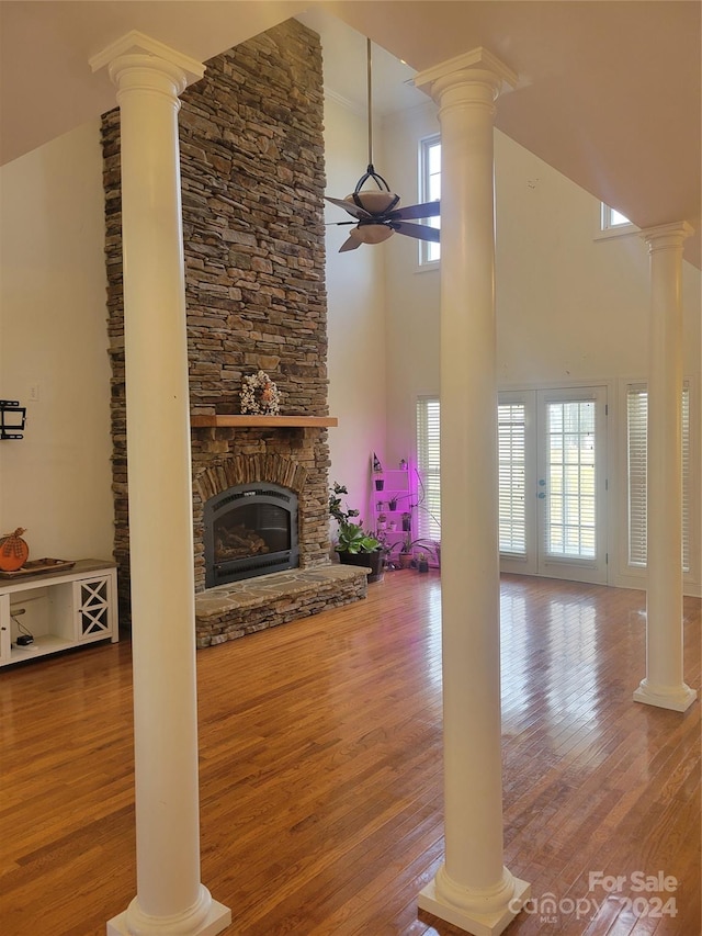 unfurnished living room featuring a stone fireplace, hardwood / wood-style flooring, and ceiling fan