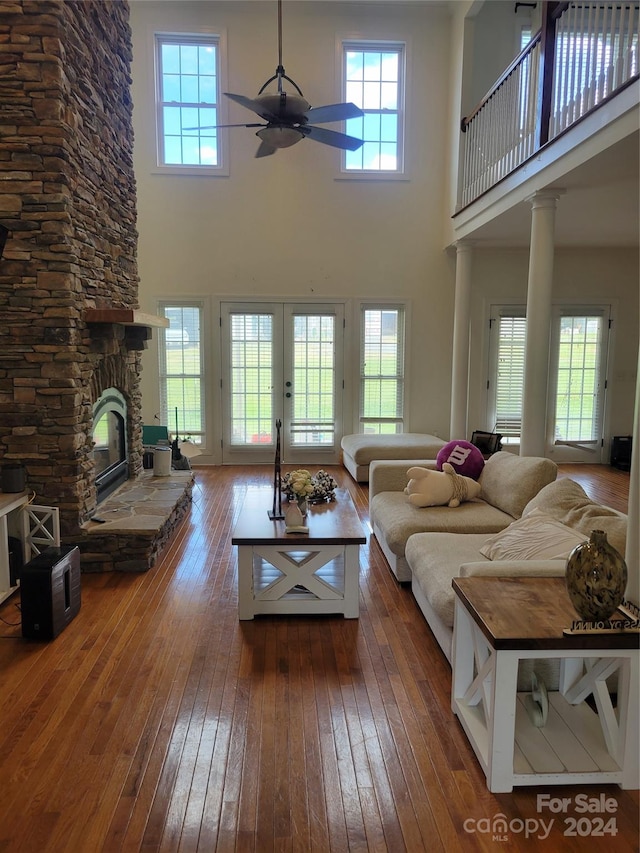 living room with a towering ceiling, hardwood / wood-style floors, a fireplace, and ceiling fan