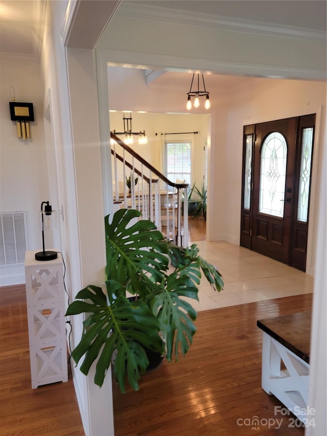 foyer with crown molding, hardwood / wood-style flooring, and an inviting chandelier