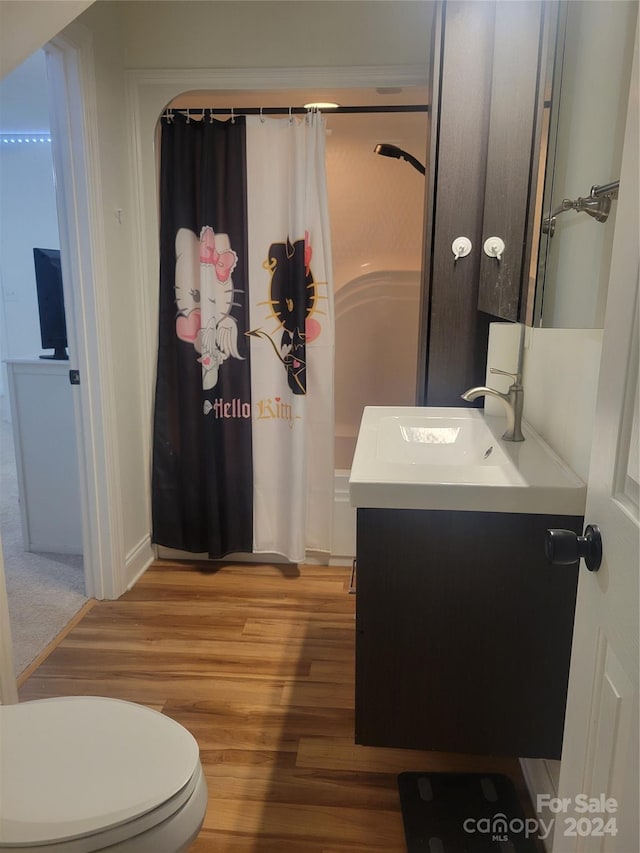 bathroom with toilet, hardwood / wood-style floors, curtained shower, and vanity