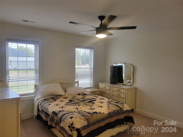 bedroom featuring multiple windows, light colored carpet, and ceiling fan