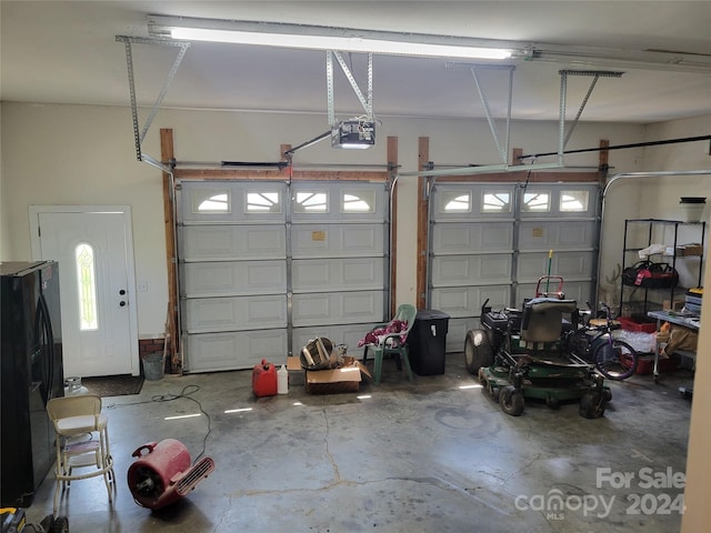 garage with a garage door opener and black fridge