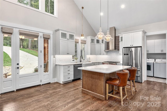 kitchen with white cabinetry, separate washer and dryer, high vaulted ceiling, a kitchen island, and stainless steel appliances