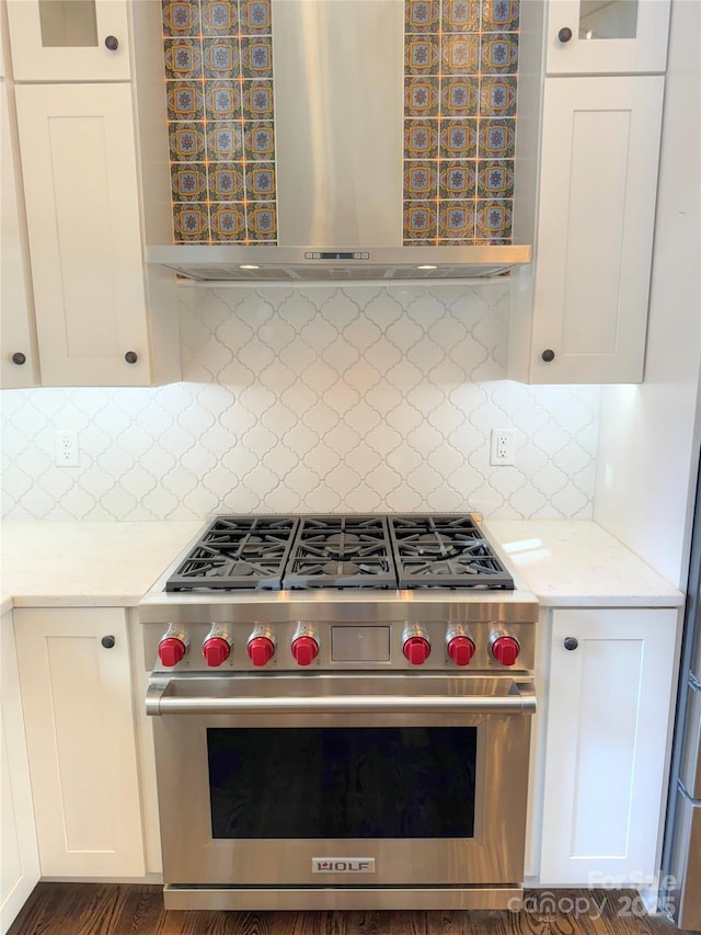 kitchen featuring white cabinets, wall chimney exhaust hood, tasteful backsplash, premium stove, and light stone counters