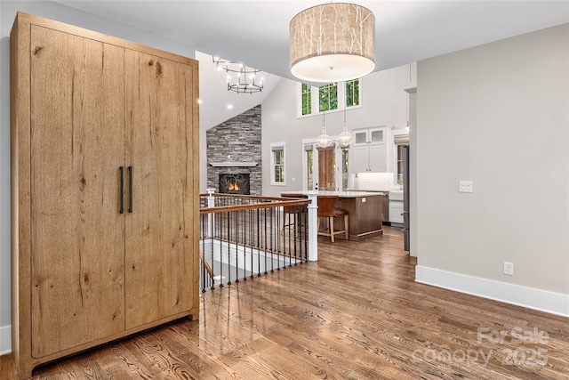 foyer entrance with a chandelier, high vaulted ceiling, a fireplace, and wood-type flooring