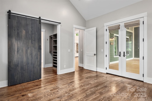 interior space featuring dark hardwood / wood-style flooring, a walk in closet, french doors, and a barn door