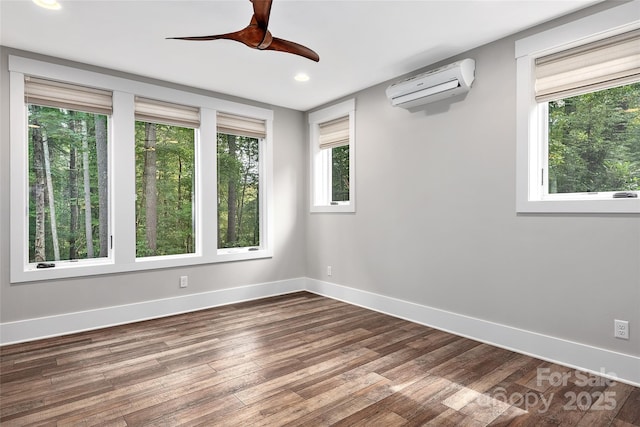 spare room with hardwood / wood-style flooring, a wall mounted AC, and ceiling fan