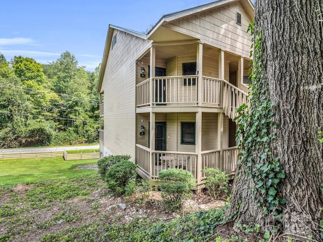 rear view of house featuring a balcony and a lawn