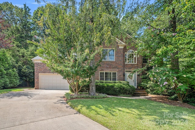 view of front of house featuring a garage, a front yard, concrete driveway, and brick siding