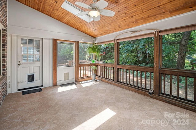 unfurnished sunroom featuring wood ceiling, vaulted ceiling with skylight, and ceiling fan