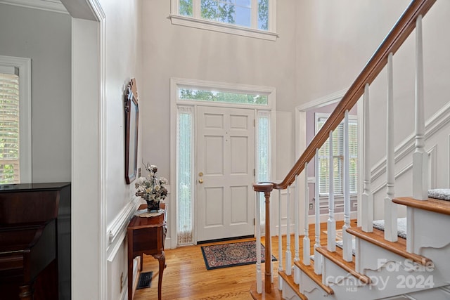 foyer entrance with light wood-type flooring and a towering ceiling