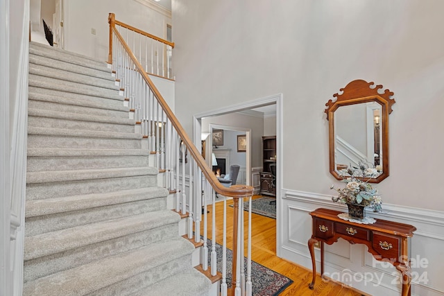 stairway featuring crown molding, a high ceiling, and hardwood / wood-style flooring