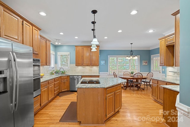 kitchen featuring appliances with stainless steel finishes, a healthy amount of sunlight, a center island, and hanging light fixtures