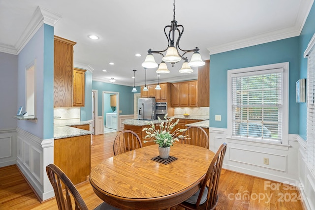 dining space with light hardwood / wood-style flooring, ornamental molding, and a chandelier