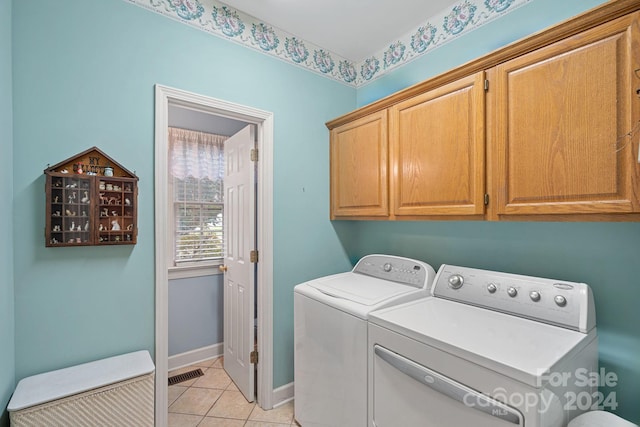 washroom featuring washing machine and dryer, cabinets, and light tile patterned flooring