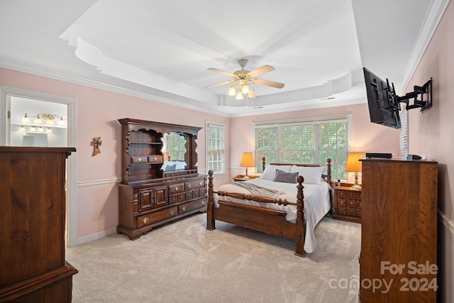 carpeted bedroom with a raised ceiling, ceiling fan, and ornamental molding