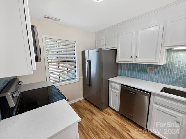 kitchen featuring light hardwood / wood-style flooring, appliances with stainless steel finishes, sink, decorative backsplash, and white cabinetry