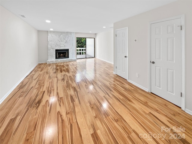 unfurnished living room featuring visible vents, baseboards, light wood-style flooring, a stone fireplace, and recessed lighting