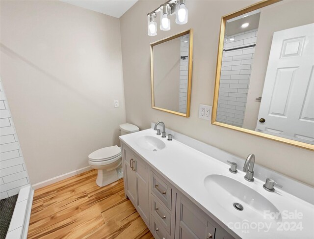 bathroom featuring hardwood / wood-style flooring, toilet, a tile shower, and vanity