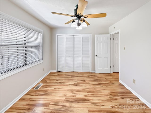 unfurnished bedroom featuring light hardwood / wood-style flooring, ceiling fan, and a closet