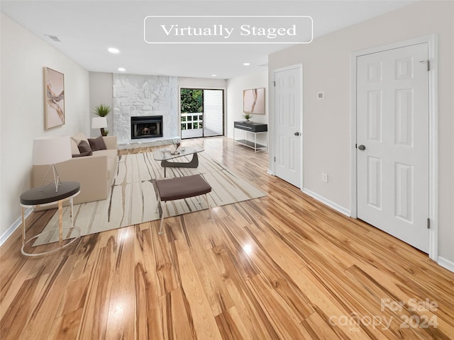 living room featuring visible vents, a fireplace, baseboards, and wood finished floors