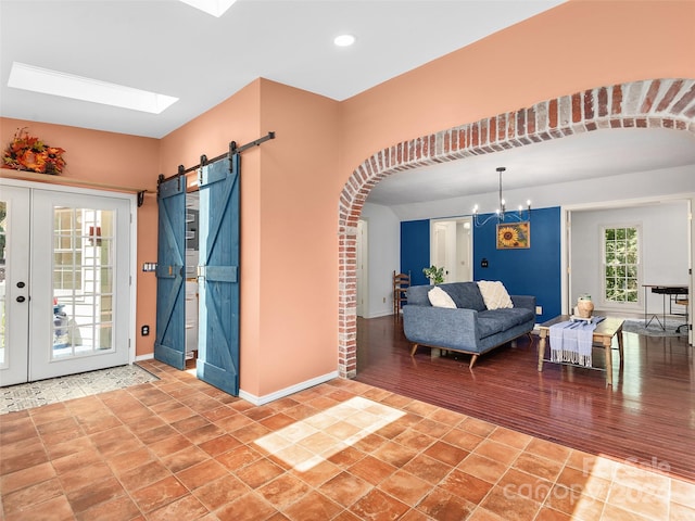 living room with a skylight, hardwood / wood-style floors, a chandelier, and a barn door