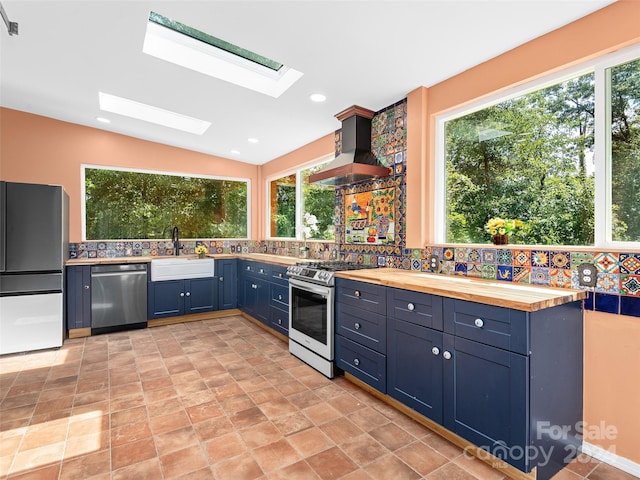 kitchen with appliances with stainless steel finishes, wooden counters, and a healthy amount of sunlight