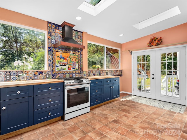 kitchen featuring a skylight, electric range, wall chimney exhaust hood, and a healthy amount of sunlight