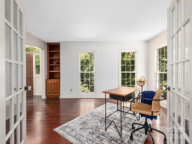 office area with built in features, dark hardwood / wood-style floors, and french doors