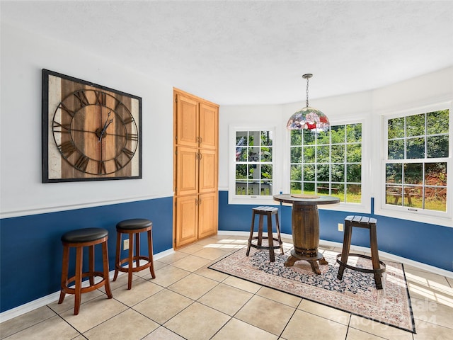 tiled dining area with a textured ceiling and a healthy amount of sunlight