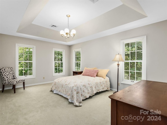 carpeted bedroom featuring a raised ceiling and a notable chandelier