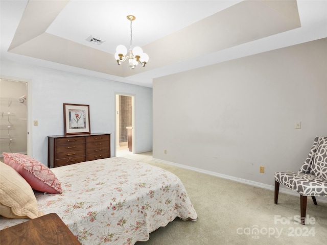 bedroom featuring a tray ceiling, light carpet, a chandelier, and a walk in closet