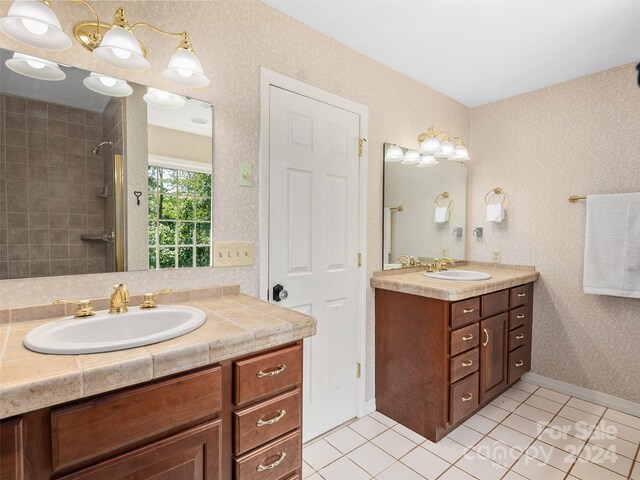 bathroom featuring tiled shower, vanity, and tile patterned flooring