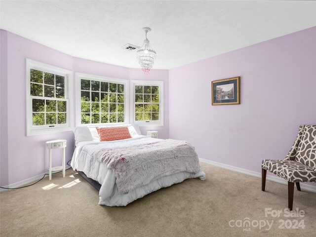 carpeted bedroom featuring an inviting chandelier