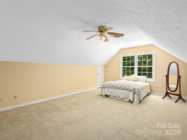 bedroom featuring a textured ceiling, light colored carpet, ceiling fan, and vaulted ceiling