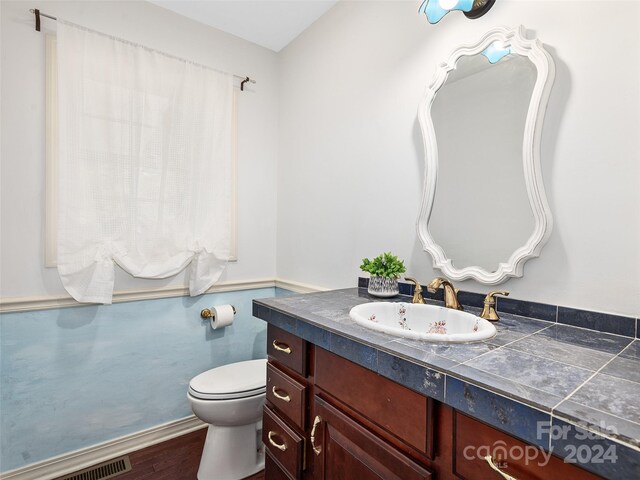 bathroom with wood-type flooring, toilet, and vanity