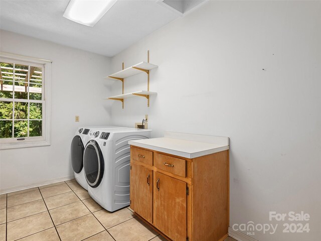 clothes washing area featuring cabinets, washing machine and clothes dryer, and light tile patterned flooring