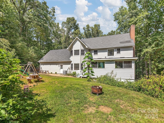 rear view of property with a fire pit and a lawn