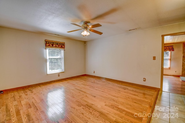 empty room featuring a textured ceiling, a wealth of natural light, ceiling fan, and light hardwood / wood-style floors