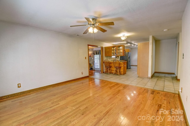 unfurnished living room featuring light wood-type flooring and ceiling fan