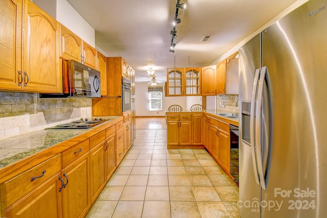 kitchen featuring track lighting, black appliances, backsplash, and light tile patterned flooring