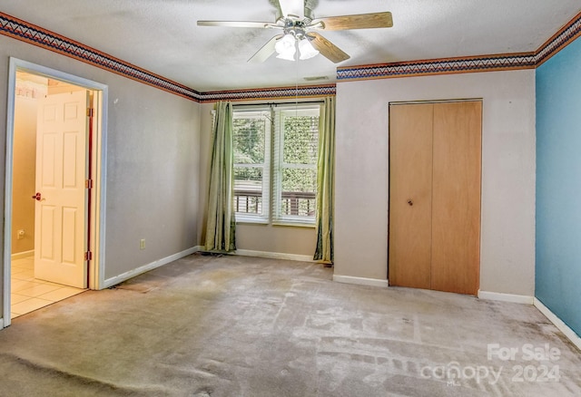 unfurnished bedroom featuring a textured ceiling, crown molding, ceiling fan, and light carpet