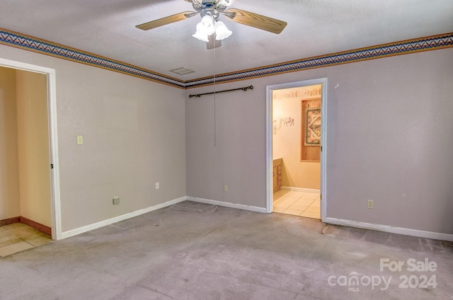 unfurnished bedroom featuring a textured ceiling, carpet flooring, connected bathroom, and ceiling fan