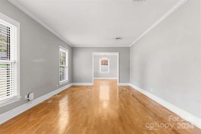 empty room featuring ornamental molding, a wealth of natural light, and hardwood / wood-style flooring