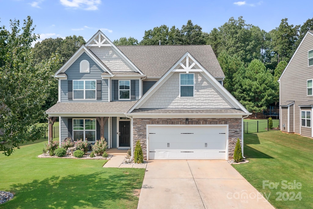 craftsman inspired home featuring a garage and a front lawn