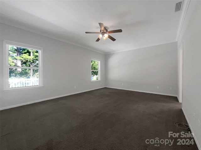 spare room featuring ornamental molding, dark carpet, and ceiling fan