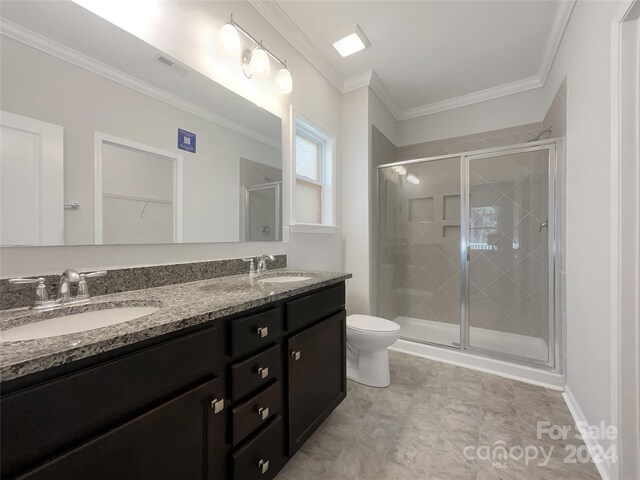 bathroom with ornamental molding, vanity, toilet, and a shower with shower door