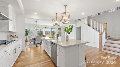 kitchen with white cabinetry, a kitchen island with sink, and hanging light fixtures