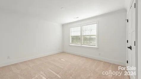 empty room with vaulted ceiling and light colored carpet